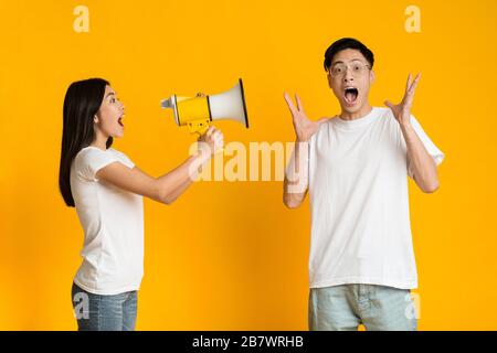 La ragazza asiatica gridando le notizie emozionanti al boyfriend usando il megaphone Foto Stock