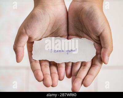 Il ragazzo che tiene pezzo di carta con la parola grazie in palma sensazione di felicità. Foto Stock