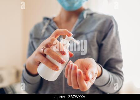 Virus Corona covid-19. Donna lava le mani con gel di alcol sapone antibatterico igienizzante indossa maschera medica. Assistenza sanitaria Foto Stock