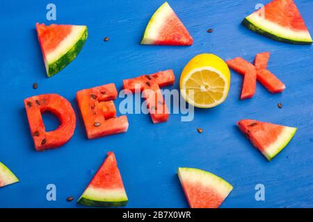 Detox di parola fatto da fette di anguria e limone. Concetto di dieta, pulizia del corpo, nutrizione sana. Sfondo blu Foto Stock