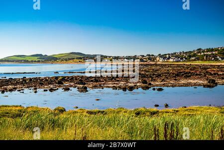 Pittoresco e tranquillo villaggio di Seamill, Scozia, visto attraverso la spiaggia rocciosa a bassa marea. Scenico paesaggio costiero scozzese. Foto Stock