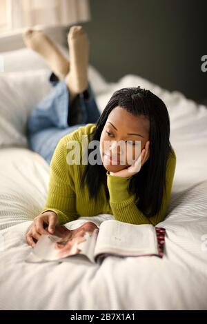 Ragazza adolescente giacente sul suo letto giorno sogno durante la lettura di una rivista. Foto Stock