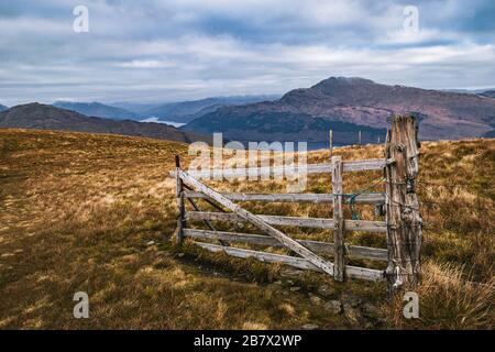 Un vecchio cancello di legno intemperato vicino alla cima di Beinn Dubh nelle Highlands scozzesi in una mattina nuvolosa, paesaggio grandangolare. Foto Stock