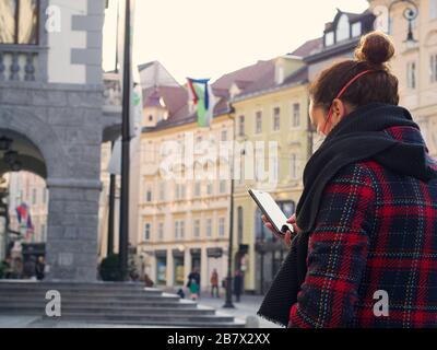 Donna che indossa la maschera di protezione facciale FFP3, dal momento che i nuovi coronavirus Sars-cov-2 sono emerse facendo attività regolari come l'uso del telefono nel centro della città. Foto Stock