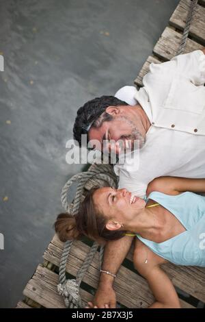 Ridendo mid-adulto giovane la condivisione di uno scherzo mentre giaceva sul loro retro su un pontile in legno. Foto Stock