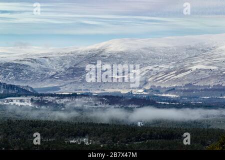 Guardando verso le piste innevate di Geal-sharn Mor dalle pendici di Cairn Gorm con Loch Morlich e il Glenmore Forest Park in primo piano Foto Stock