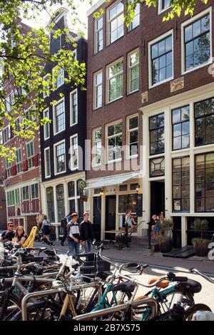 Vista della gente che cammina sulla strada all'area del ponte di Armbrug ad Amsterdam. Molte biciclette parcheggiate e edifici storici e tradizionali sono anch'essi in vista. Foto Stock