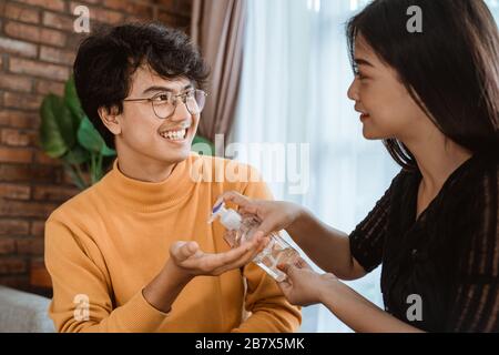 donna asiatica e uomo con igienizzatore a mano a casa Foto Stock