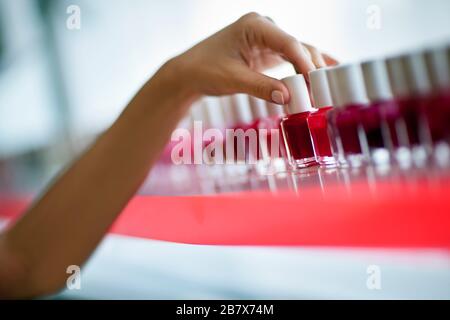 Mano su una donna media adulto che sceglie un colore smalto del chiodo ad un salone di bellezza. Foto Stock