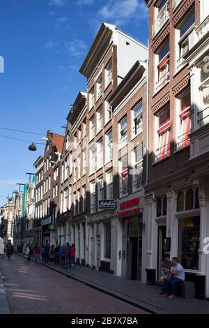 Vista sulle persone che camminano su Warmoesstraat Street ad Amsterdam. E' una delle strade piu' antiche con molti caffe', ristoranti e negozi. È una somma soleggiata Foto Stock