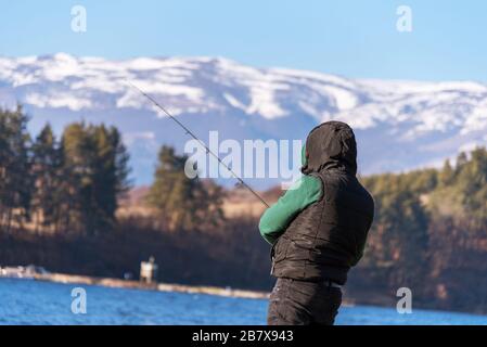 Un pescatore maschio sul lago è in piedi in acqua e la pesca per una canna da pesca. Concetto di vacanza hobby di pesca. Spazio di copia. Foto Stock