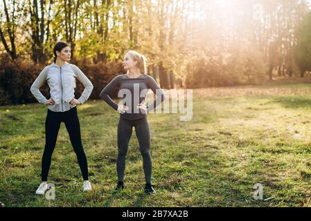 Due fidanzate stanno facendo esercizi in natura, guardandosi l'un l'altro. Foto Stock
