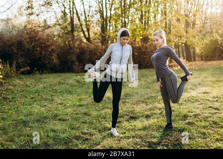 Fitness mattutino nel parco. Due ragazze stanno facendo esercizi. Foto Stock