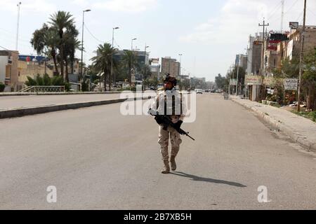 Baghdad, Iraq. 18 Marzo 2020. Un membro della sicurezza irachena è visto su una strada vuota a Baghdad, Iraq, il 18 marzo 2020. Come una delle misure precauzionali contro lo scoppio della COVID-19, le autorità irachene hanno imposto un coprifuoco di una settimana nella capitale di Baghdad, a partire dal marzo 17 al 23. Credito: Khalil Dawood/Xinhua/Alamy Live News Foto Stock