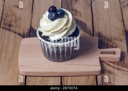 Muffin al cioccolato con crema bianca e mirtillo. Foto Stock