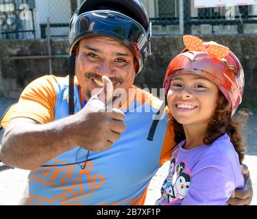 Uomo che mostra i pollici-up segno con sua figlia accanto a lui, West End Village, Roatan, Honduras Foto Stock