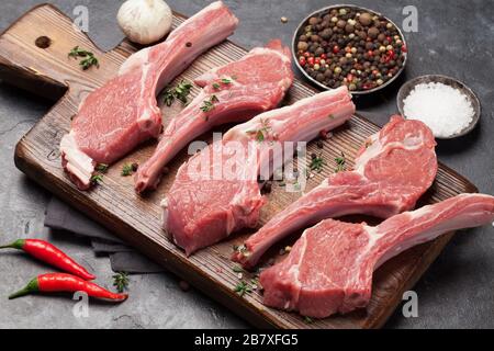 Costolette di agnello in cucina. Stinco di agnello crudo con spezie e condimenti Foto Stock