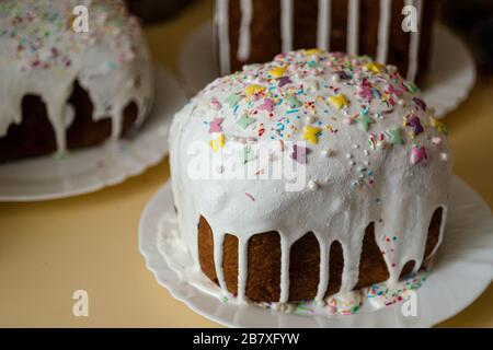 Tradizionale deliziosa celebrazione pane pasquale con glassa bianca e polvere di caramelle colorate su un piatto. Concetto di festa ortodossa annuale artigianale Foto Stock