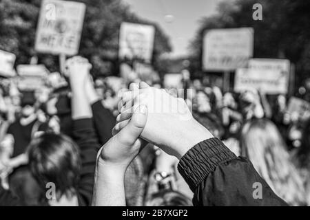 fotografia in bianco e nero di due persone che si uniscono le mani in un venerdì per la futura protesta sul cambiamento climatico, simbolo della forza Foto Stock