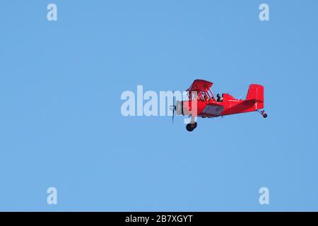 Biplano rosso in volo in una giornata di sole Foto Stock