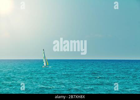 Piccola barca a vela personale in mare aperto in piano in una giornata estiva. Calma stagione con cielo blu. Giornata di sole nel mar mediterraneo a Tel Aviv Foto Stock