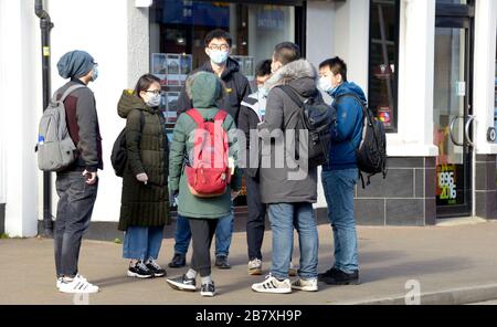 Grande gruppo di studenti cinesi in maschere, parlando per strada, a Nottingham, Inghilterra Foto Stock