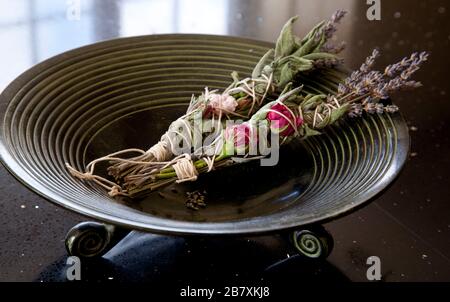 Salvia, rosa e lavanda si insinuano in una ciotola bruciante Foto Stock