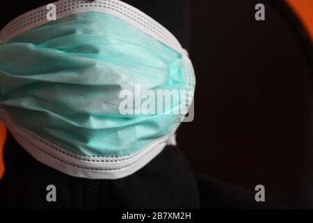 Un misterioso individuo con cappuccio irriconoscibile con felpa scura indossa una normale maschera chirurgica blu in italia Foto Stock