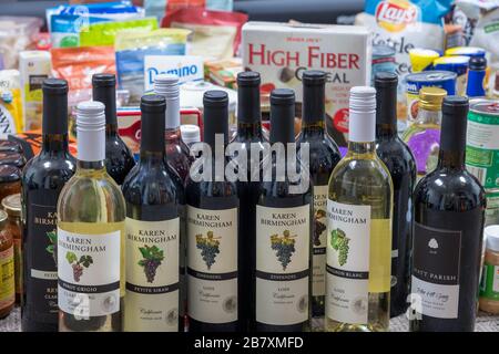 Morgantown, WV - 18 marzo 2020: Selezione di generi alimentari per la conservazione a domicilio durante la quarantena a causa dell'epidemia di Coronavirus con particolare attenzione alle bottiglie di vino Foto Stock