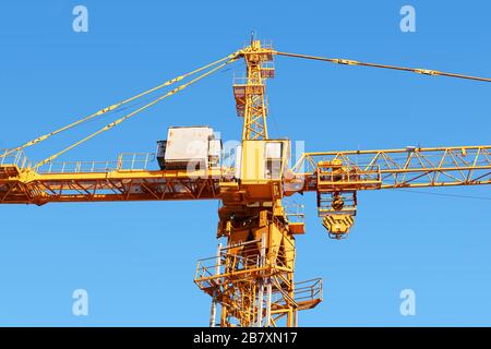 frammento di una gru a torre da costruzione gialla con cabina contro un cielo blu Foto Stock