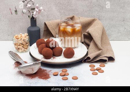 Liquore freddo al caffè con tartufo al cioccolato, arrotolato in polvere di cacao su fondo grigio Foto Stock