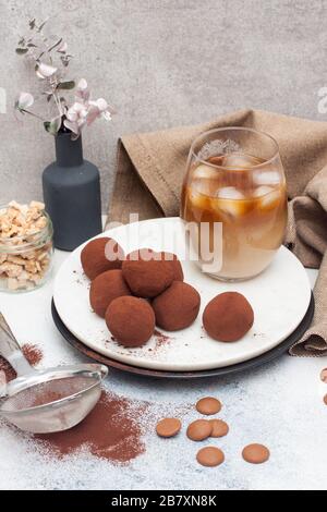 Liquore freddo al caffè con tartufo al cioccolato, arrotolato in polvere di cacao su fondo grigio Foto Stock