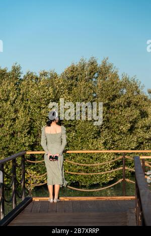 Turista femminile godendo il tramonto al parco lungomare Mangrove Walk ad Abu Dhabi, Emirati Arabi Uniti Foto Stock