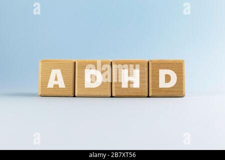 Disturbo da deficit di attenzione iperattività (ADHD). Abbreviazione di testo su cubi/blocchi di legno su sfondo blu chiaro. Disturbo mentale più comunemente diagnosticato Foto Stock