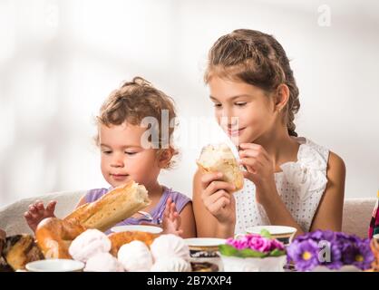 I bambini piccoli e divertenti mangiano pane fresco e panini durante la colazione. Concetto sano e per bambini con buon appetito. Concetto di menu per bambini. CopySpace Foto Stock