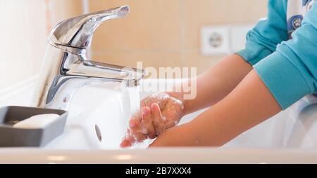 Lavaggio mani bambino risciacquo sapone con acqua corrente al lavello, prevenzione Coronavirus igiene delle mani. Protezione pandemica Covid-19 mediante pulizia delle braccia Foto Stock