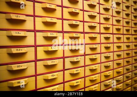 Guardia di sicurezza un grande cabinet giallo con celle e numeri per la memorizzazione di file personali e piccoli dettagli. Concetto di immagazzinare cose importanti o docu Foto Stock