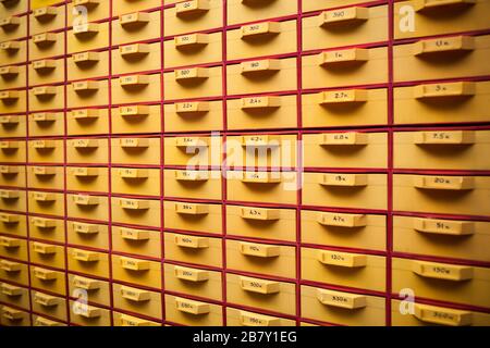 Guardia di sicurezza un grande cabinet giallo con celle e numeri per la memorizzazione di file personali e piccoli dettagli. Concetto di immagazzinare cose importanti o docu Foto Stock