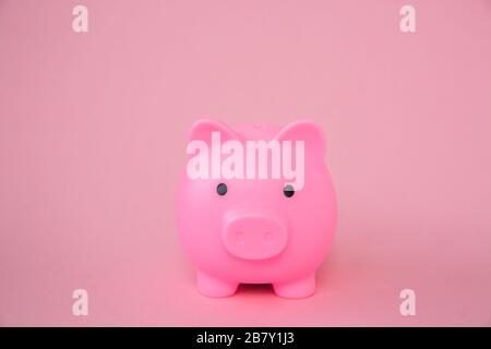Una Piggy Bank rosa per bambini su uno sfondo rosa con spazio copia in un'immagine di sfondo di concetto di risparmio Foto Stock
