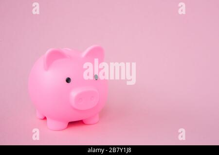 Una Piggy Bank rosa per bambini su uno sfondo rosa con spazio copia in un'immagine di sfondo di concetto di risparmio Foto Stock