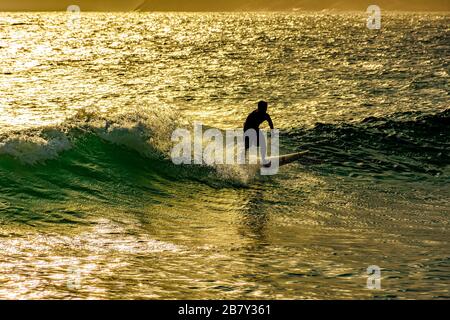 Surfista sulle onde della spiaggia di Ipanema a Rio de Janeiro durante il tramonto in estate Foto Stock