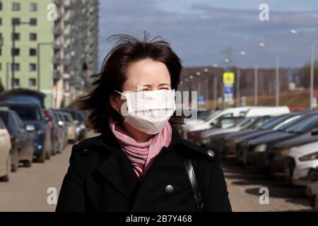 Protezione coronavirus, donna in maschera medica a piedi su una strada della città in sole primavera giorno. Concetto di raffreddore e influenza, assistenza sanitaria Foto Stock