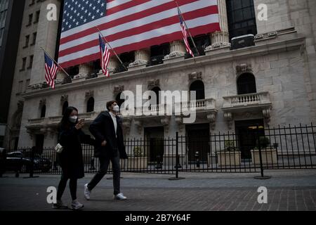 New York, Stati Uniti. 18 Marzo 2020. I pedoni che indossano maschere facciali passano davanti alla Borsa di New York (NYSE) a New York, negli Stati Uniti, il 18 marzo 2020. Il New York Stock Exchange (NYSE) ha detto mercoledì che chiuderà temporaneamente il suo trading floor e si sposterà verso il commercio elettronico a causa dello scoppio del COVID-19. Credit: Michael Nagle/Xinhua/Alamy Live News Foto Stock