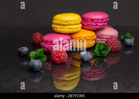 biscotti colorati amaretto lampone mirtillo menta fresca su sfondo nero Foto Stock