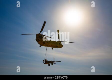 Un elicottero Chinook CH-47 solleva un howitzer da 155 mm trainato M777 alla base al QA'im, Iraq, 9 marzo 2020. A causa del successo delle operazioni contro l'ISIS da parte delle forze di sicurezza irachene, le forze della coalizione si sono riposizionate in altre basi irachene per continuare la partnership anti-ISIS. (STATI UNITI Foto dell'esercito di SPC. Andrew Garcia) Foto Stock