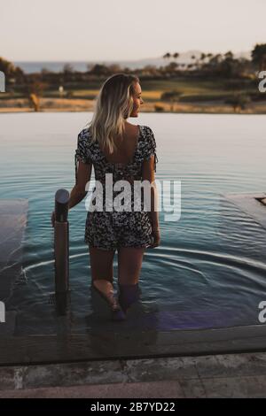Giovane donna che si rilassa nella piscina messicana durante il tramonto Foto Stock