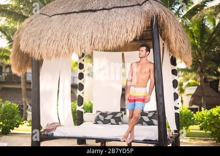 Godendo del sole caldo alla spiaggia messicana - giovane uomo in vacanza riposante nell'ombra Foto Stock