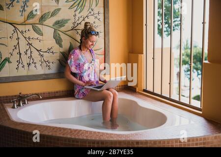 Giovane donna che lavora durante le vacanze in Messico immergendo i suoi piedi nella vasca idromassaggio Foto Stock