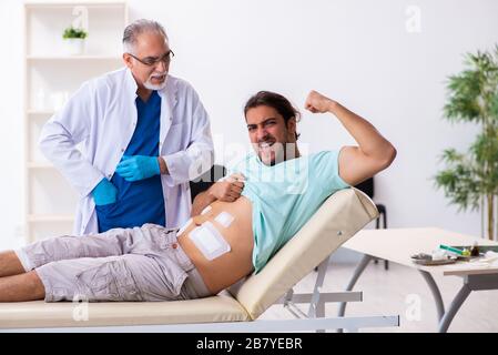 Uomo ferito che visita medico esperto di sesso maschile Foto Stock