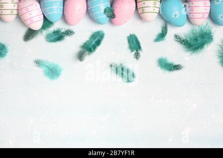 Concetto di Pasqua. Uova e piume color pastello su sfondo chiaro con spazio per il testo. Vista dall'alto, disposizione piatta. Foto Stock